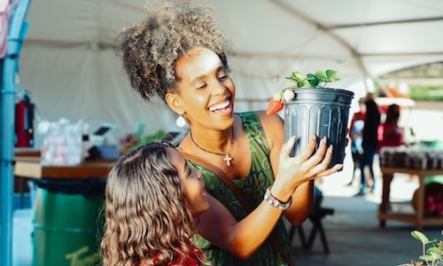 a woman and a girl looking at a plant