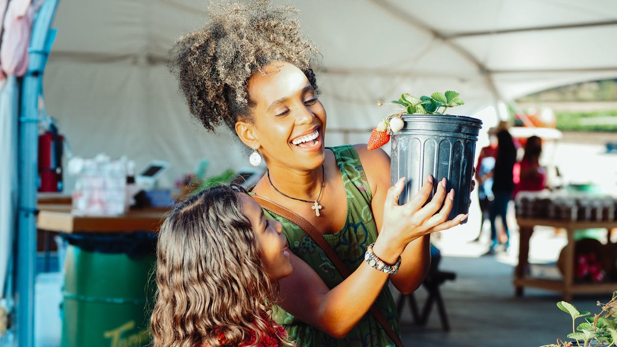 mother and daughter picking out potted strawberry plant together